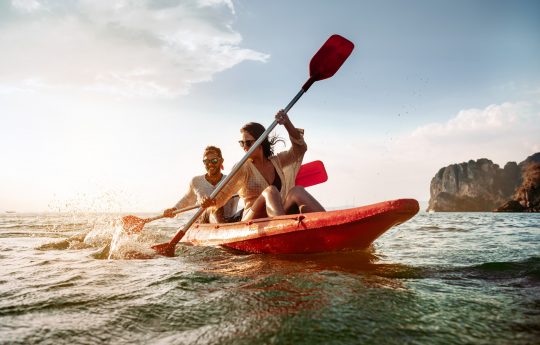 Happy couple walks by sea kayak or canoe at tropical bay